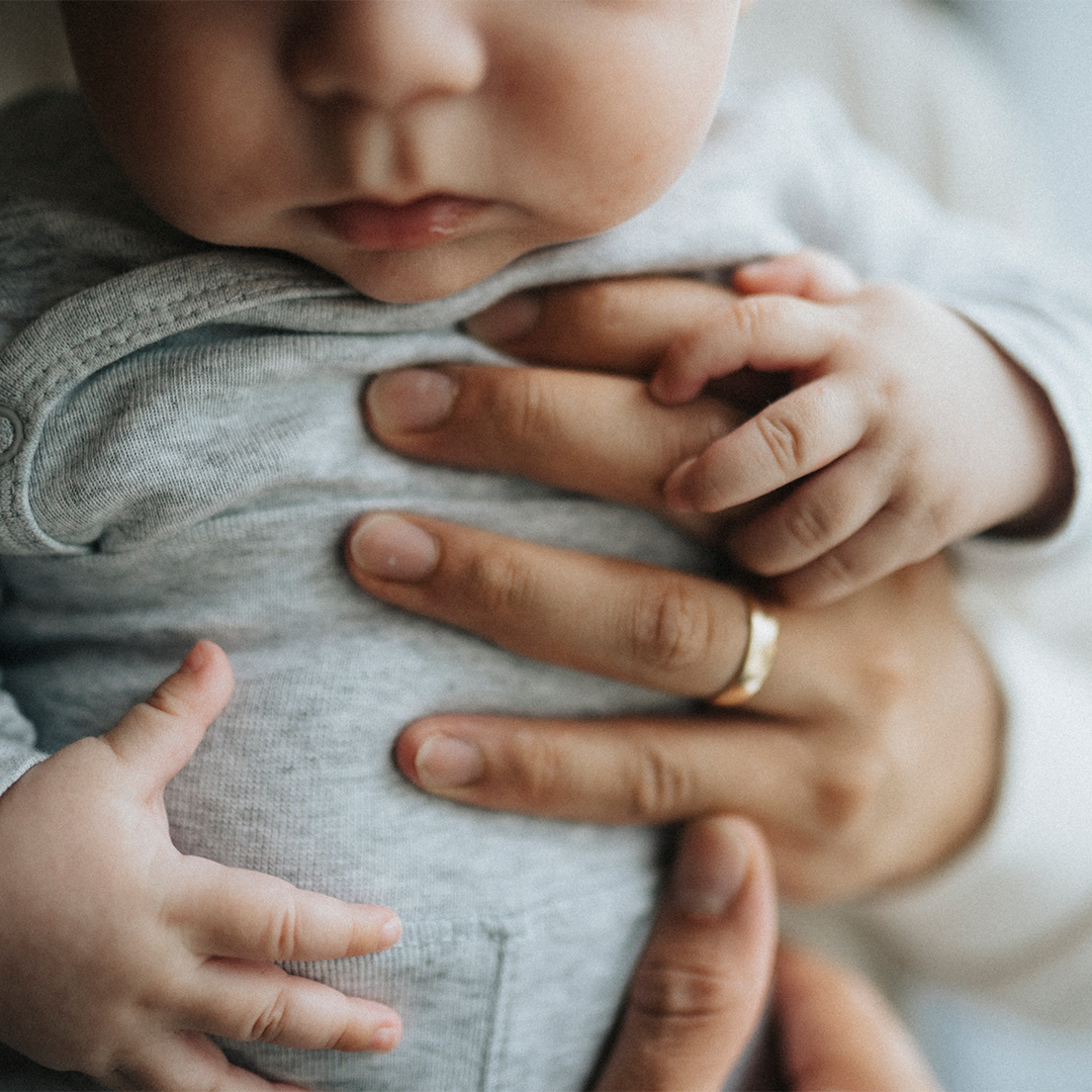 Parents hands holding baby